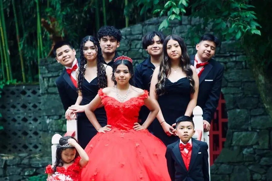 Quinceañera in red with her court and family